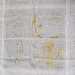 May include: White cotton handkerchief with a delicate design of three yellow fish swimming among green reeds. The handkerchief is signed "by Mushkin" in the bottom right corner.