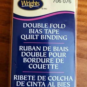May include: Package of red double fold bias tape for quilting. The package is labeled "Wrights" and "706 076". It says "Double Fold Bias Tape Quilt Binding" and includes measurements of 3 yards or 2.74 meters and .875 inches wide.
