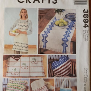 May include: A craft pattern for making a table runner, pillow, tote bag, and heart-shaped pillow. The pattern includes instructions for creating a variety of designs, including a cherry motif, a chevron pattern, and a blue and white striped design. The pattern is titled "McCall's Crafts 3694".