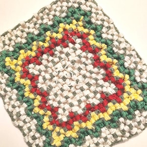 May include: A crocheted square potholder with a white background and a colorful border. The border is made of green, yellow, and red yarn.