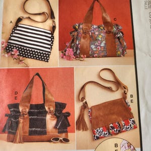 May include: A McCall's M8467 sewing pattern envelope featuring illustrations of four different bag styles labeled A, B, C, D, and E. The designs include various handbags and crossbody bags with floral, striped, and solid patterns, plus a small illustration.
