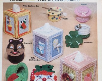 May include: A collection of plastic canvas shapes for needlepoint projects. The shapes include a tissue box, a bonnet, a palette, a shamrock, a chipmunk, a strawberry, a clown face, and a floral design. The shapes are all white with colorful embroidery.