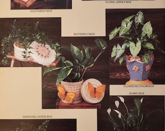 May include: A collection of decorative plant containers, each with a unique design. The containers include a Southwest box, Floral Array box, Butterfly box, Flower Blossom box, Bunny box, and Carousel Horse box. The containers are filled with plants and have lids.