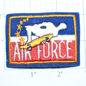 May include: A blue, red, and white embroidered patch with a white figure skateboarding and the text "AIR FORCE".