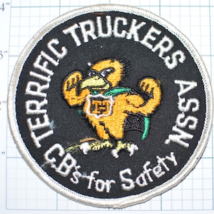 May include: A black and white embroidered patch with a white border. The patch features a cartoon yellow bird with a green cape and the text "TERRIFIC TRUCKERS ASSN. CB's for Safety".