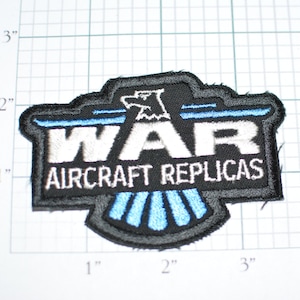 May include: Black and white embroidered patch with a blue and white eagle design. The patch reads "WAR AIRCRAFT REPLICAS".