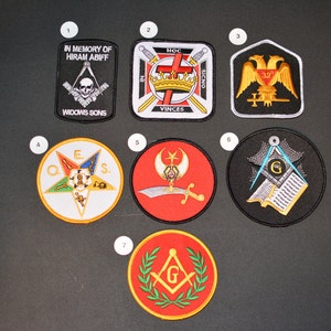 May include: Seven round embroidered patches with Masonic symbols. The patches are white, black, red, and gold with various symbols including a skull and crossbones, a crown, a sword, a compass, a square, and a star.