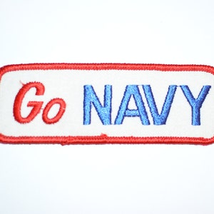 May include: Red and white embroidered patch with the text "Go NAVY" in blue.