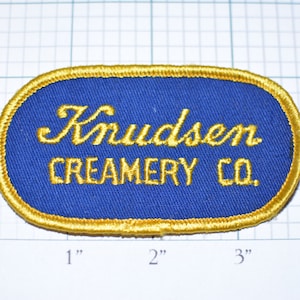 May include: A blue and gold embroidered patch with the text "Knudsen Creamery Co."
