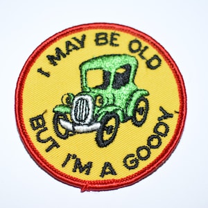 May include: Embroidered patch with a yellow background and a red border. The patch features a green vintage car and the text "I MAY BE OLD BUT I'M A GOODY".