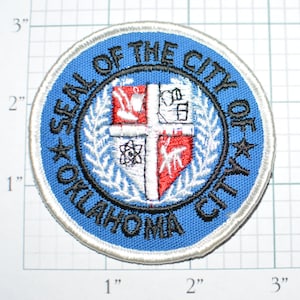 May include: A blue and white embroidered patch with the text "SEAL OF THE CITY OF OKLAHOMA CITY" surrounding a white and red crest with a cross and other symbols.
