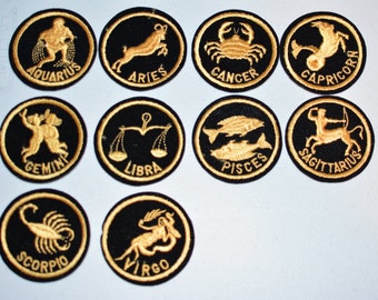 May include: Twelve black felt zodiac patches with gold embroidery. Each patch features a different zodiac sign: Aquarius, Aries, Cancer, Capricorn, Gemini, Libra, Pisces, Sagittarius, Scorpio, Virgo.