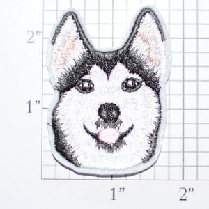 May include: Embroidered iron-on patch of a husky dog's face. The dog has black and white fur and is smiling with its tongue sticking out.