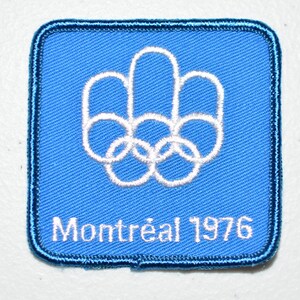 May include: Blue fabric patch with white embroidered Olympic rings and the text "Montréal 1976".