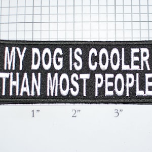 May include: Black and white embroidered patch with the text "My dog is cooler than most people".