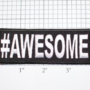 May include: Black iron-on patch with white embroidered text that reads "#AWESOME" measuring approximately 3 inches wide by 1 inch tall.