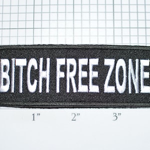 May include: Black embroidered patch with white text that reads "BITCH FREE ZONE". The patch is approximately 3 inches wide and 1 inch tall.