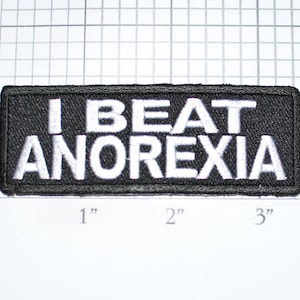 May include: Black embroidered patch with white text that reads "I BEAT ANOREXIA".