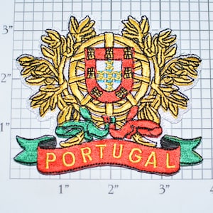 May include: Embroidered patch featuring the coat of arms of Portugal, with a red shield, gold crown, and a blue sphere. The patch has a green and red ribbon with the word "PORTUGAL" in gold lettering.