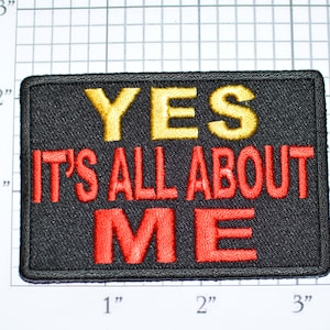 May include: Black embroidered patch with the text "YES IT'S ALL ABOUT ME" in red and yellow thread. The patch is approximately 2 inches by 3 inches.
