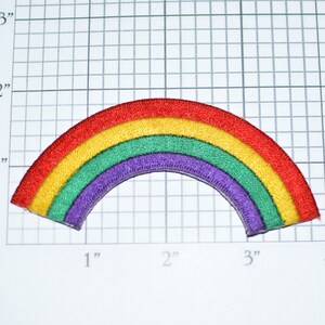 May include: A rainbow-colored felt patch in the shape of an arch. The patch is approximately 3 inches wide and 1 inch tall. The colors of the rainbow are red, orange, yellow, green, blue, and purple.
