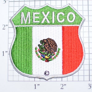May include: Embroidered patch in the shape of a shield, featuring the colors of the Mexican flag: green, white, and red. The word "MEXICO" is at the top. The center displays the Mexican coat of arms, including an eagle and a snake.