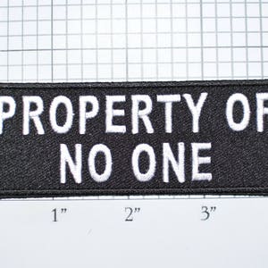 May include: Black rectangular patch with the text "PROPERTY OF NO ONE" in white, embroidered lettering. The patch is approximately 4 inches long and 1 inch high.
