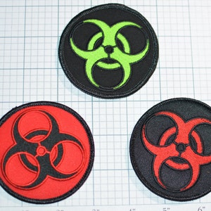 May include: Three embroidered patches with a biohazard symbol. The patches are black with a red, green, and black biohazard symbol in the center.