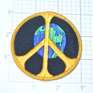May include: A round, gold peace sign patch with a black background and a blue and green globe in the center.