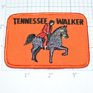 May include: Orange fabric patch with embroidered black text "TENNESSEE WALKER" and a black and gray horse with a rider in a red coat.