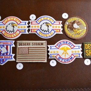 May include: A collection of eight embroidered patches featuring the Desert Shield and Desert Storm logos. The patches are in various colors, including blue, red, white, yellow, and green. The patches feature eagles, stars, and the words "Desert Shield", "Desert Storm", "Thunder & Lightning", and "Persian Gulf".