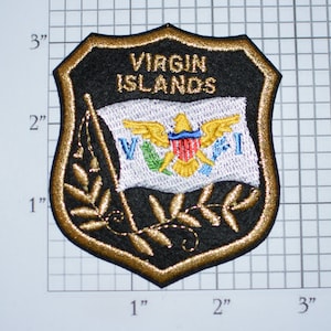 May include: A black and gold embroidered patch with the words "VIRGIN ISLANDS" and a white flag with a yellow eagle and blue, red, green, and white accents. The flag is surrounded by a gold laurel wreath.