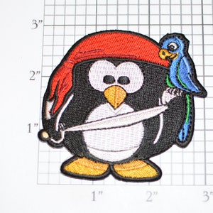 May include: A black and white penguin wearing a red pirate hat and holding a sword. The penguin has a blue and green parrot perched on its shoulder.