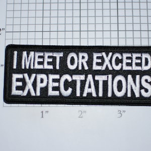May include: Black and white embroidered patch with the text "I MEET OR EXCEED EXPECTATIONS".