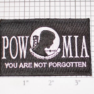 May include: Black embroidered patch with white lettering that reads "POW MIA YOU ARE NOT FORGOTTEN". The patch features a white silhouette of a person's head with a barbed wire fence and a watchtower.