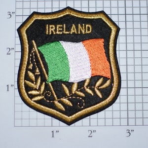 May include: A gold and black embroidered patch with the Irish flag and the word "IRELAND" in white lettering.