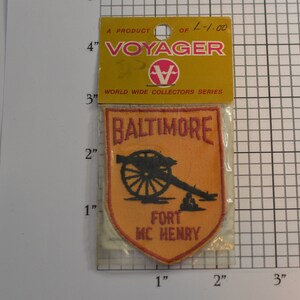 May include: A vintage Voyager World Wide Collectors Series patch featuring a silhouette of a cannon and the text "Baltimore Fort McHenry". The patch is orange with red lettering and is packaged in a clear plastic bag.