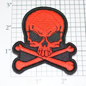 May include: Red skull and crossbones patch with black background. The skull is detailed with black eyes and a black mouth. The patch is approximately 2 inches wide.