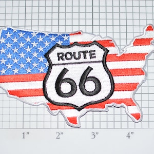 May include: Embroidered patch in the shape of the United States, featuring the American flag and a Route 66 sign. The patch is approximately 5 inches wide and 3 inches tall. The Route 66 sign is white with black text and border.