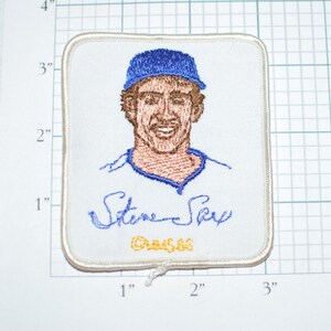 May include: White embroidered patch with a blue baseball cap, a smiling man's face, and the signature "Steve Sax" with the year "1986" underneath.