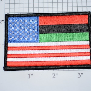 May include: A red, white, and blue American flag patch with a black, red, and green stripe across the top. The patch is approximately 2 inches wide and 3 inches long.