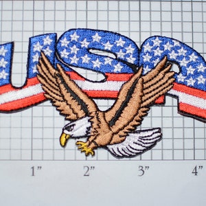 May include: Embroidered patch with the word "USA" in red, white, and blue with a bald eagle flying in front of it.