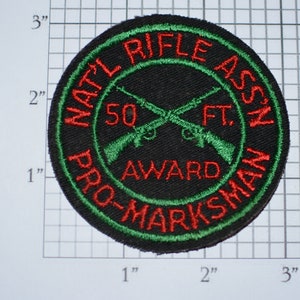 May include: A black, green, and red embroidered patch with the text "NAT'L RIFLE ASS'N PRO-MARKSMAN 50 FT. AWARD".