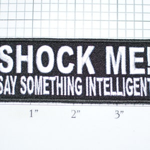 May include: Black embroidered patch with white text that reads "SHOCK ME! SAY SOMETHING INTELLIGENT".