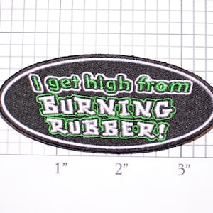 May include: Black and white embroidered patch with green outline. The patch is oval shaped and reads "I get high from BURNING RUBBER!"