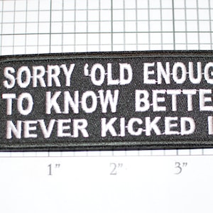 May include: Black embroidered patch with white text that reads "Sorry 'Old Enough To Know Better' Never Kicked In".