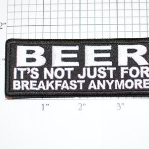 May include: Black and white embroidered patch with the text "BEER IT'S NOT JUST FOR BREAKFAST ANYMORE".