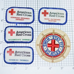 May include: Five American Red Cross patches, including a round patch with a red cross and the text "Swim Stay Fit 50 Miles". The other patches are rectangular and feature a red cross and the text "American Red Cross" with different swimming levels.