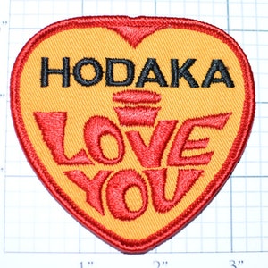 May include: A yellow heart-shaped patch with red embroidered lettering that reads "HODAKA LOVE YOU".
