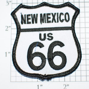 May include: White and black embroidered patch with the text "NEW MEXICO" and "US 66" in a shield shape.
